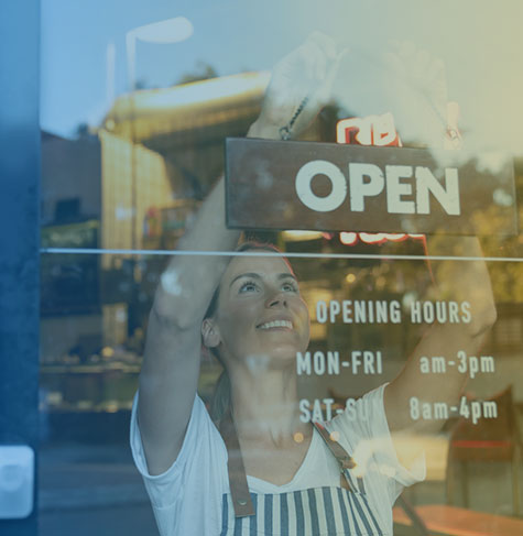 Business owner putting up open sign in business window